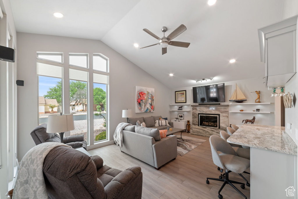 Living area with recessed lighting, light wood finished floors, ceiling fan, a high end fireplace, and high vaulted ceiling