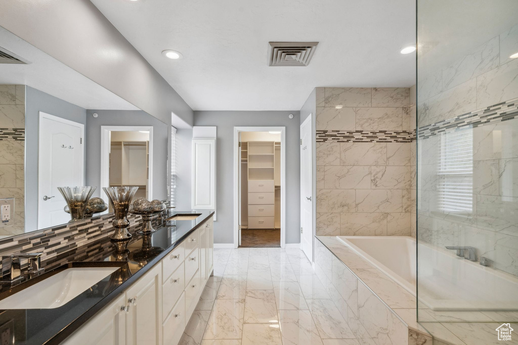 Bathroom featuring marble finish floors, baseboards, tiled bath, recessed lighting, and a spacious closet