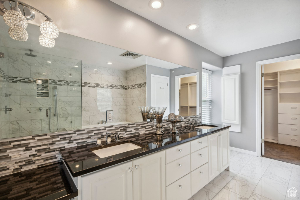 Full bath with a stall shower, baseboards, a spacious closet, double vanity, and recessed lighting