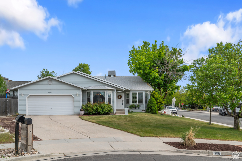 Single story home featuring a garage, a front lawn, and concrete driveway