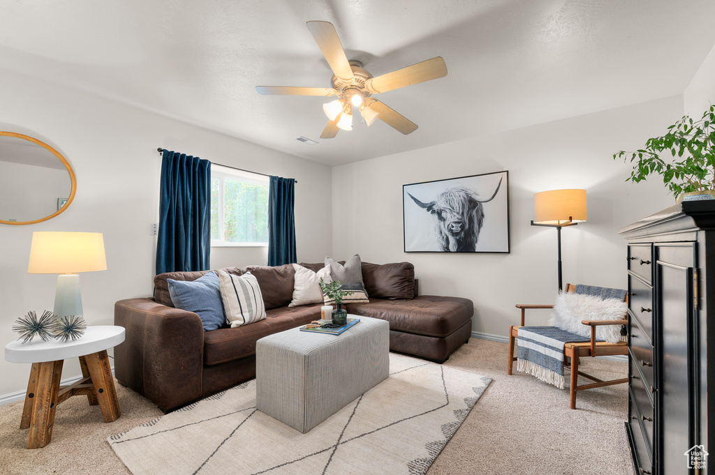 Living area with light carpet, a ceiling fan, and baseboards