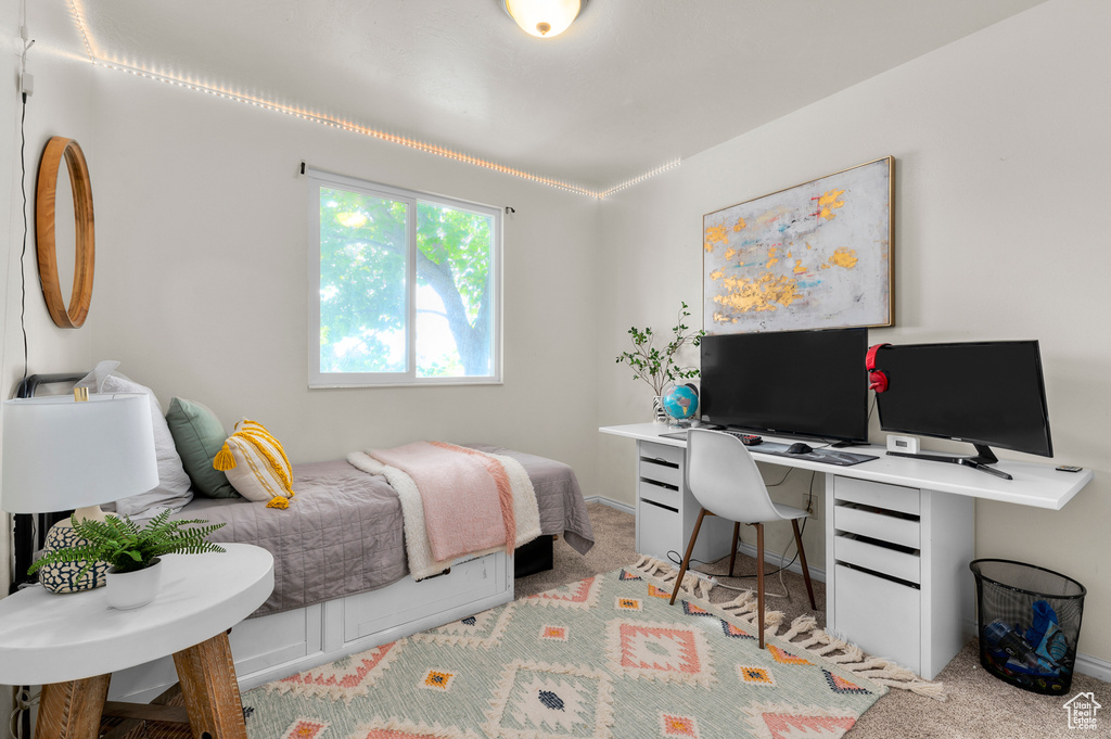 Bedroom with light carpet and an office area