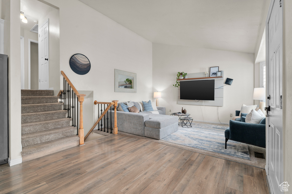 Living room featuring vaulted ceiling, wood finished floors, and stairway