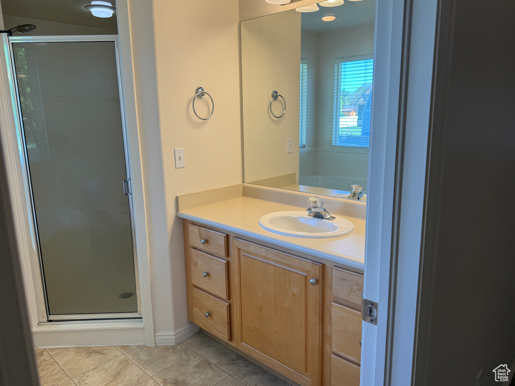 Full bathroom featuring a stall shower, vanity, tile patterned floors, and baseboards