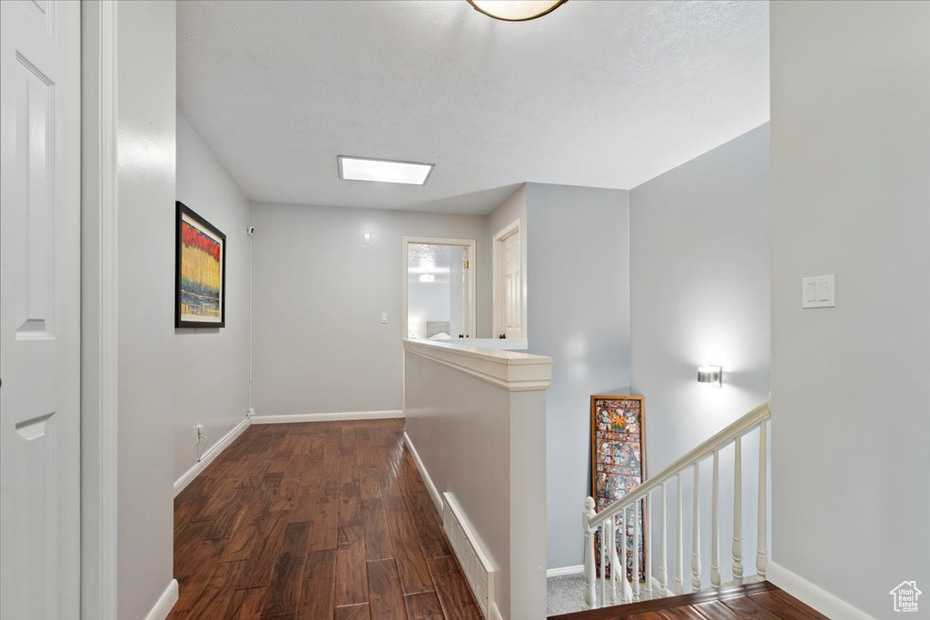Hall featuring an upstairs landing, baseboards, and wood finished floors