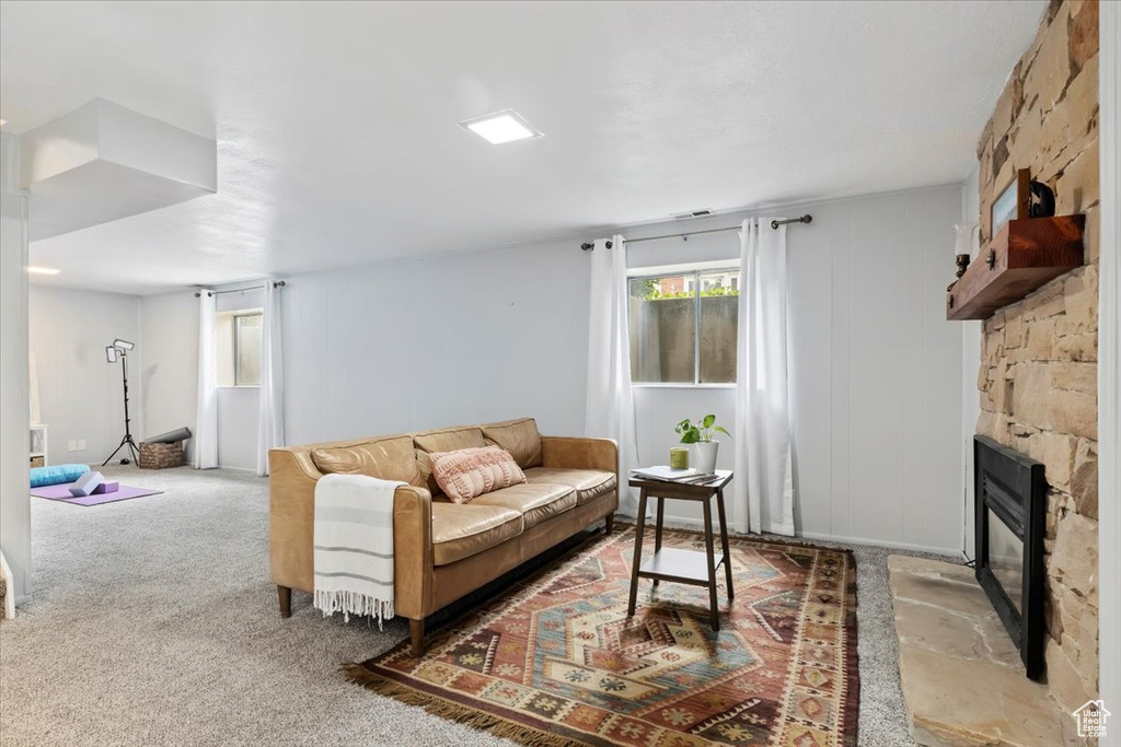 Carpeted living area featuring a stone fireplace