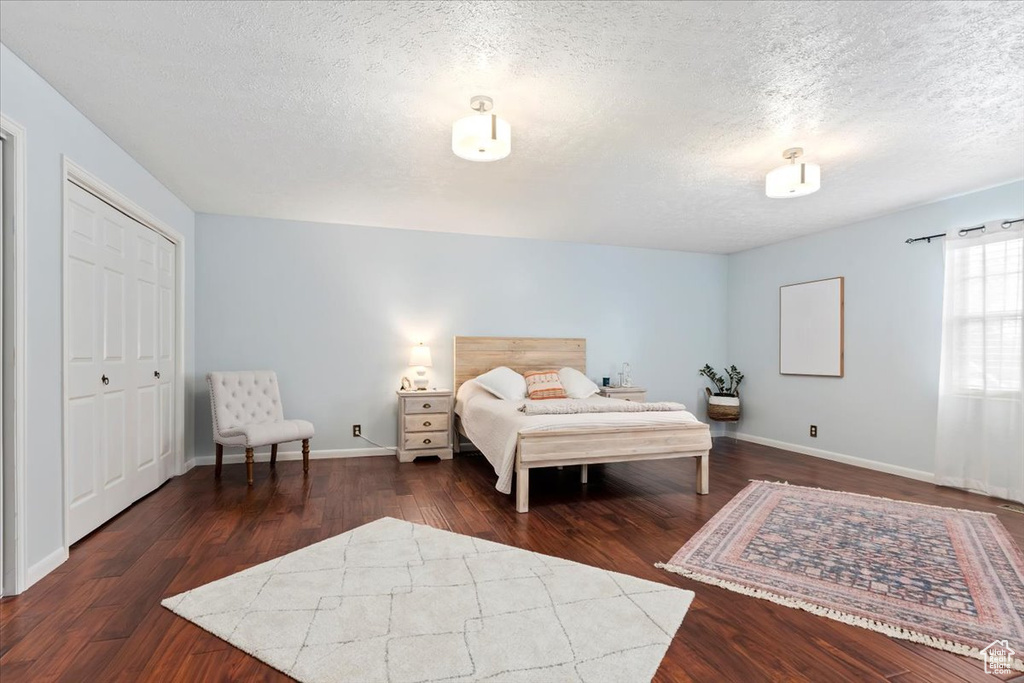 Bedroom featuring a textured ceiling, wood finished floors, and baseboards