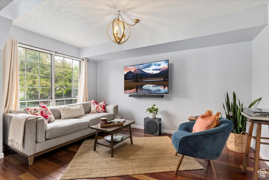 Living area with a chandelier, wood finished floors, baseboards, and a textured ceiling