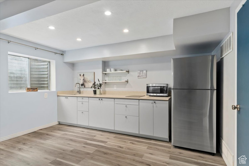 Kitchen featuring appliances with stainless steel finishes, white cabinetry, light countertops, a sink, and recessed lighting
