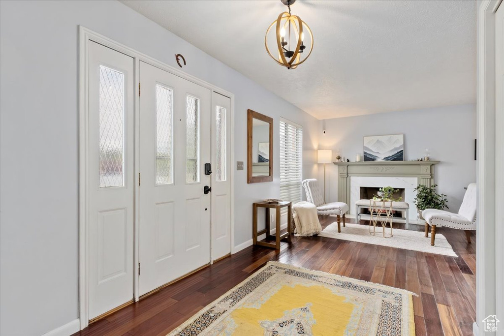 Entryway featuring hardwood / wood-style floors, a premium fireplace, a chandelier, and baseboards