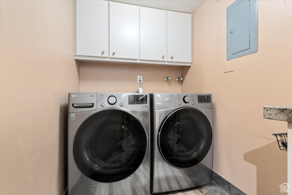 Laundry area with cabinet space, electric panel, and washing machine and clothes dryer