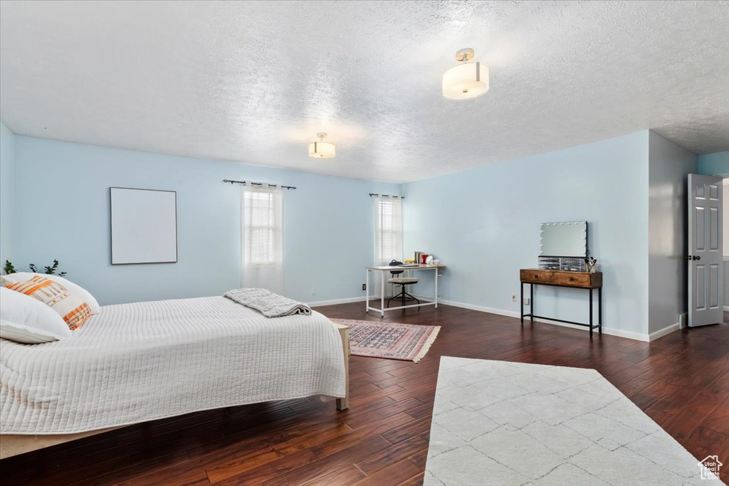Bedroom with wood finished floors, a textured ceiling, and baseboards