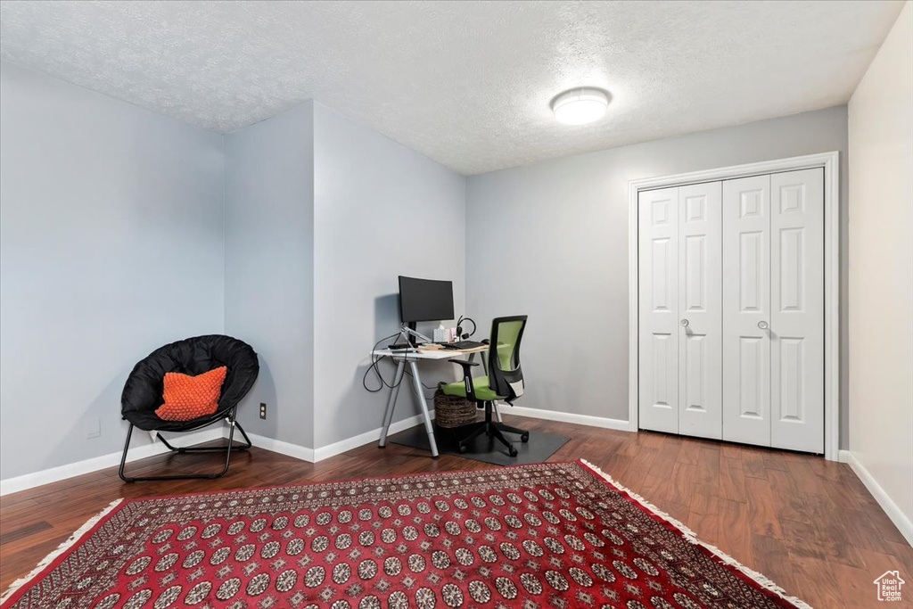 Office with wood finished floors, a textured ceiling, and baseboards