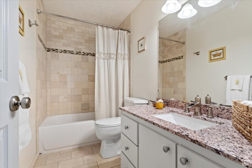 Full bathroom with toilet, shower / tub combo with curtain, vanity, and tile patterned floors
