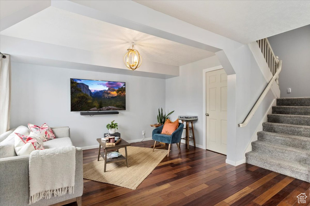 Living room with dark wood finished floors, stairway, a chandelier, and baseboards