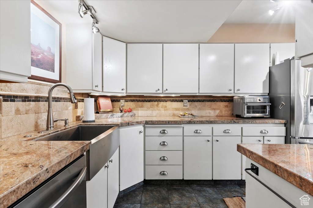 Kitchen featuring appliances with stainless steel finishes, white cabinets, and decorative backsplash