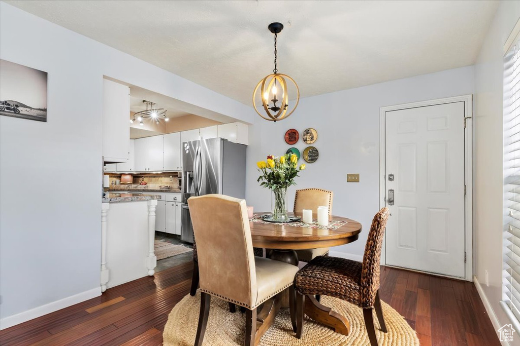 Dining area featuring a chandelier, dark wood-type flooring, and baseboards
