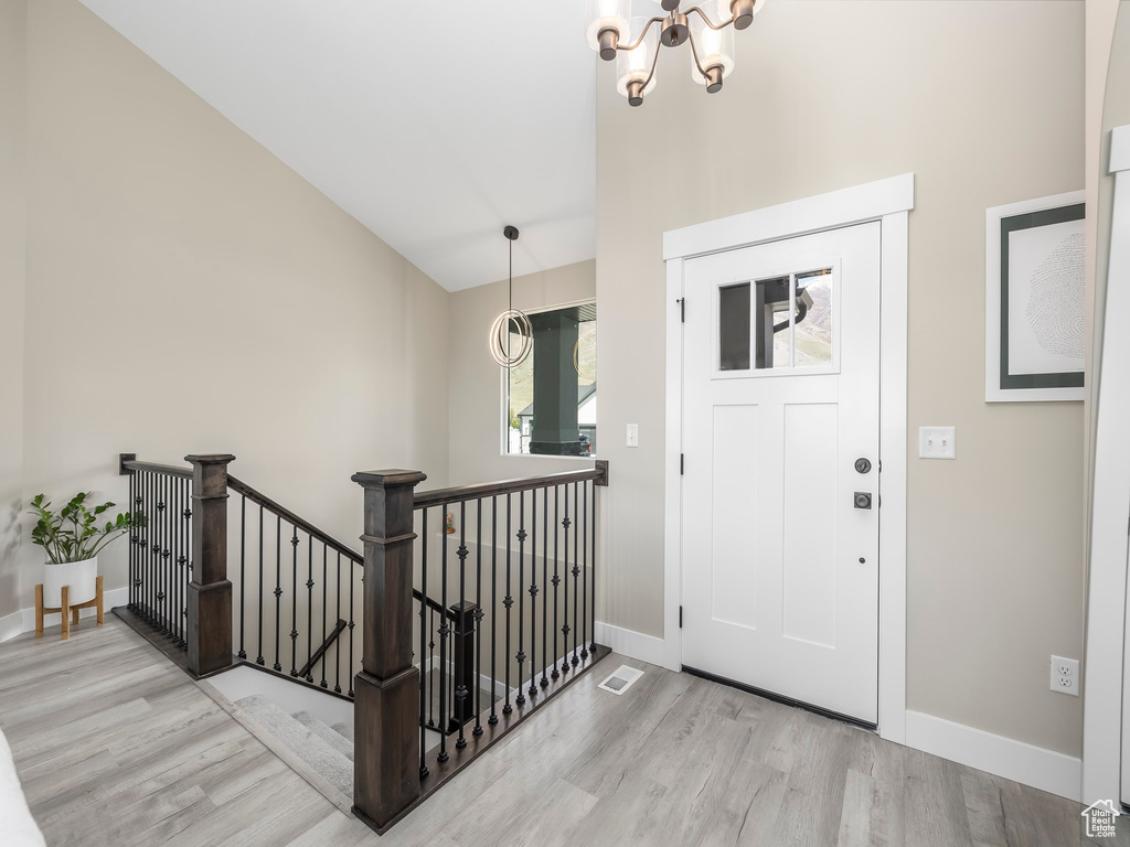 Foyer featuring an inviting chandelier, baseboards, and wood finished floors