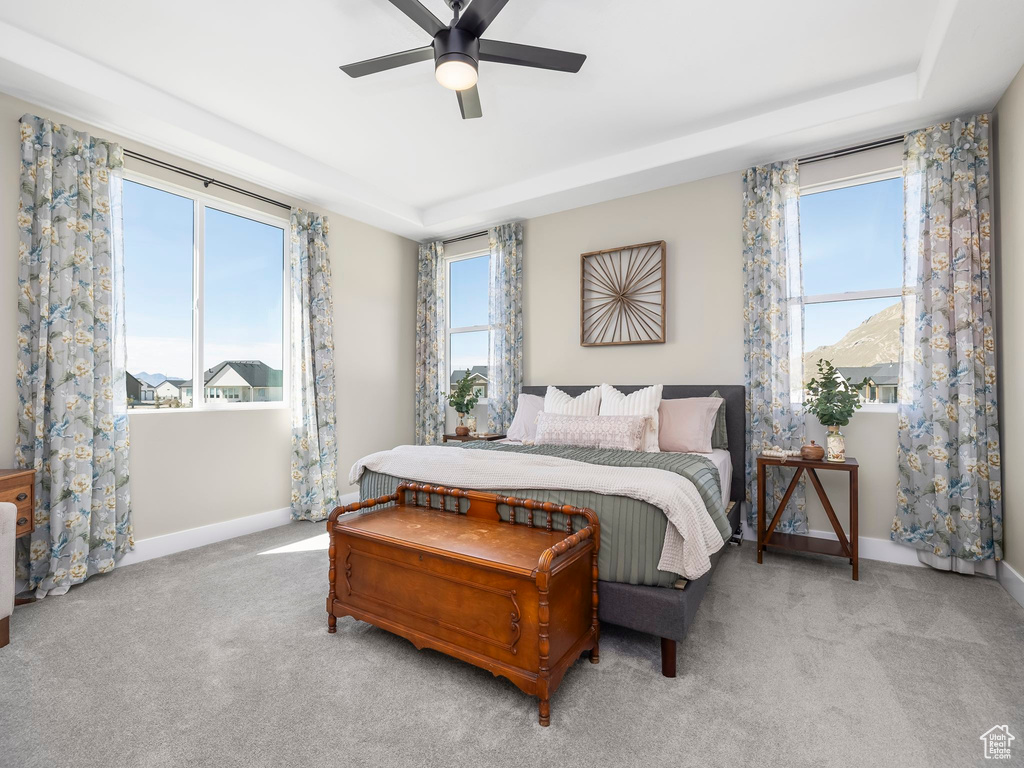 Bedroom with baseboards, ceiling fan, a tray ceiling, and carpet floors