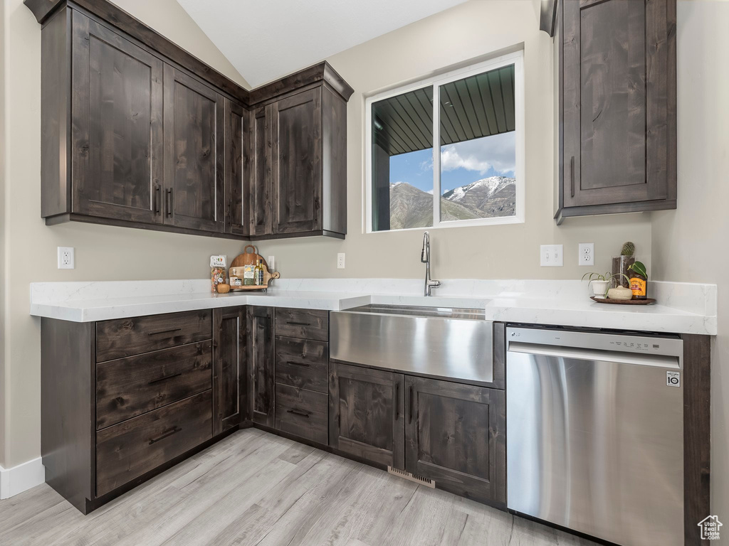Kitchen featuring dark brown cabinetry, a sink, dishwasher, light wood-style flooring, and vaulted ceiling
