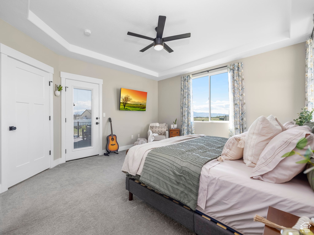 Bedroom with carpet floors, access to exterior, baseboards, a raised ceiling, and a ceiling fan