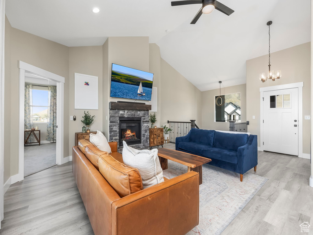 Living room with baseboards, vaulted ceiling, plenty of natural light, and light wood finished floors