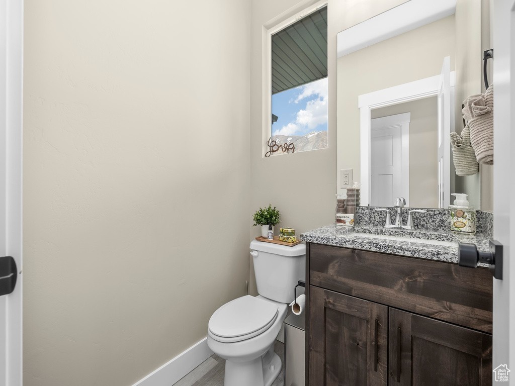 Half bath featuring vanity, baseboards, and toilet