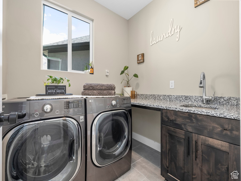 Laundry area with a sink, baseboards, tile patterned flooring, and washing machine and clothes dryer