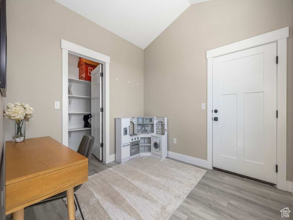 Office featuring baseboards, light wood-style flooring, and lofted ceiling