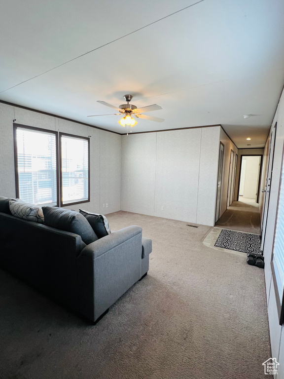 Living room featuring carpet, a decorative wall, and a ceiling fan
