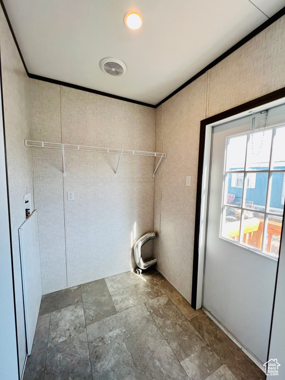Clothes washing area featuring ornamental molding, hookup for a washing machine, stone finish flooring, and visible vents