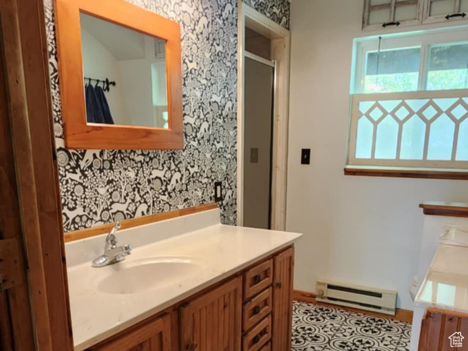Bathroom featuring baseboard heating, baseboards, a stall shower, and vanity