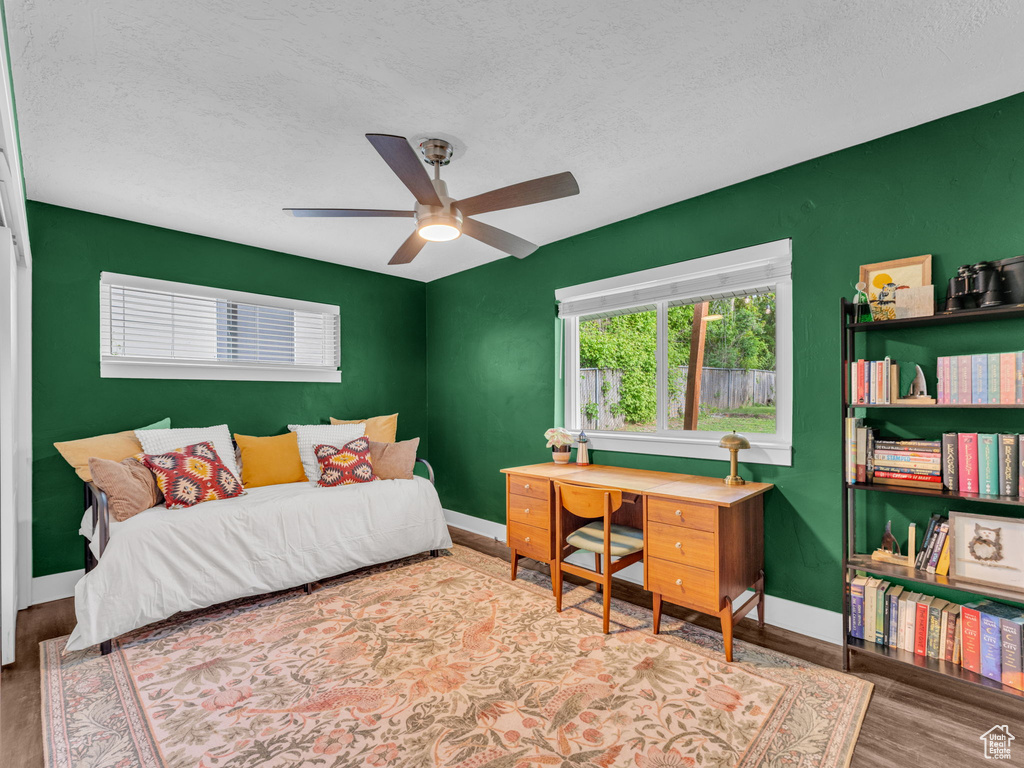 Bedroom featuring wood finished floors, a textured ceiling, baseboards, and ceiling fan