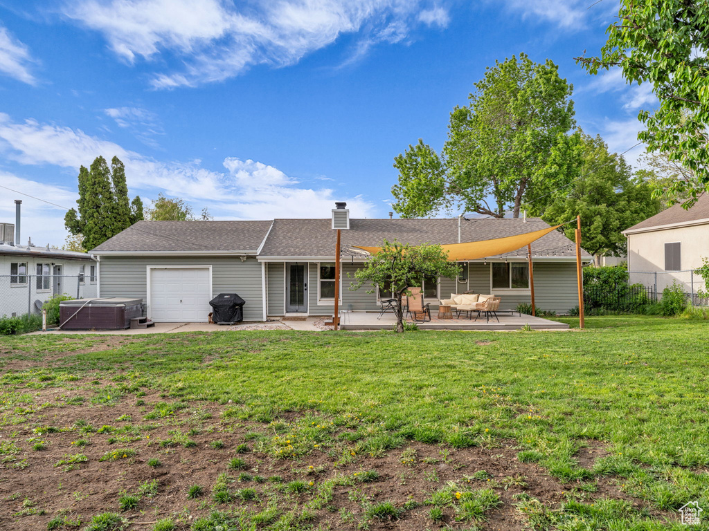 Back of property featuring a hot tub, a patio area, an attached garage, central AC unit, and a chimney