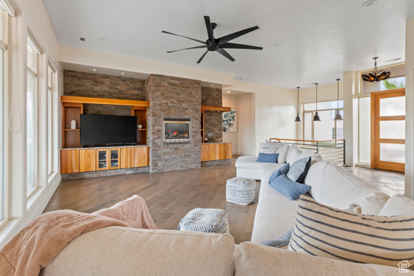 Living room featuring ceiling fan, wood finished floors, recessed lighting, and a stone fireplace