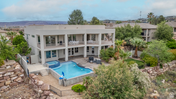 Rear view of property featuring a balcony, a fenced backyard, a patio area, and stucco siding