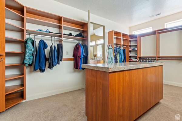 Walk in closet with light colored carpet