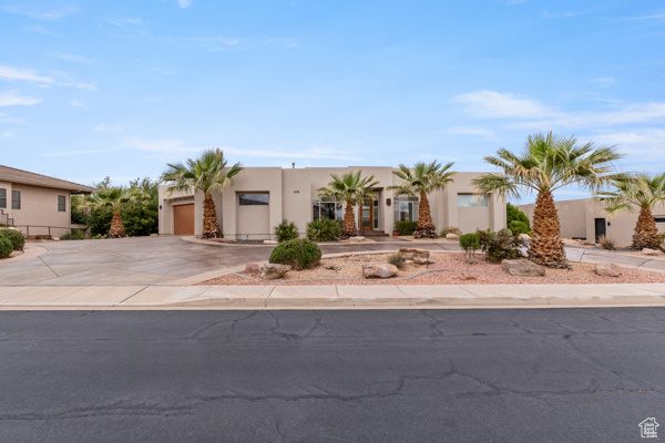 View of front of property with stucco siding, driveway, an attached garage, and fence