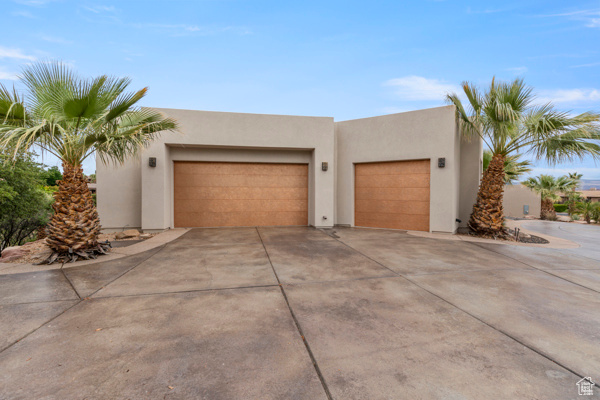 View of front facade featuring driveway, stucco siding, and a garage