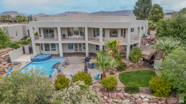 Back of property with a patio, stucco siding, a balcony, a mountain view, and a pool with connected hot tub