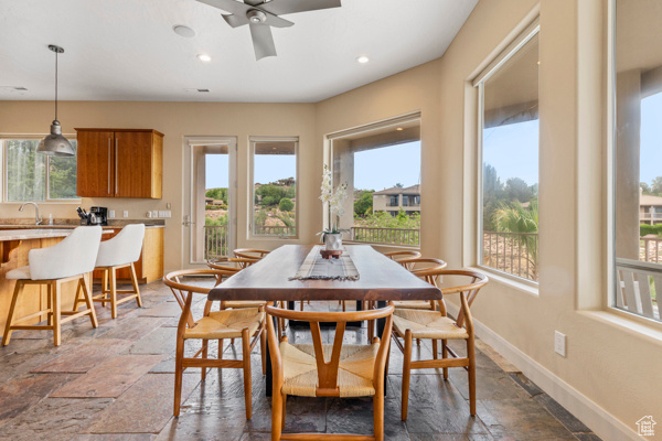 Dining room with stone tile floors, ceiling fan, baseboards, and recessed lighting