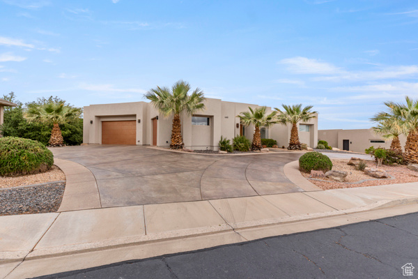 Pueblo-style home with curved driveway, stucco siding, and an attached garage