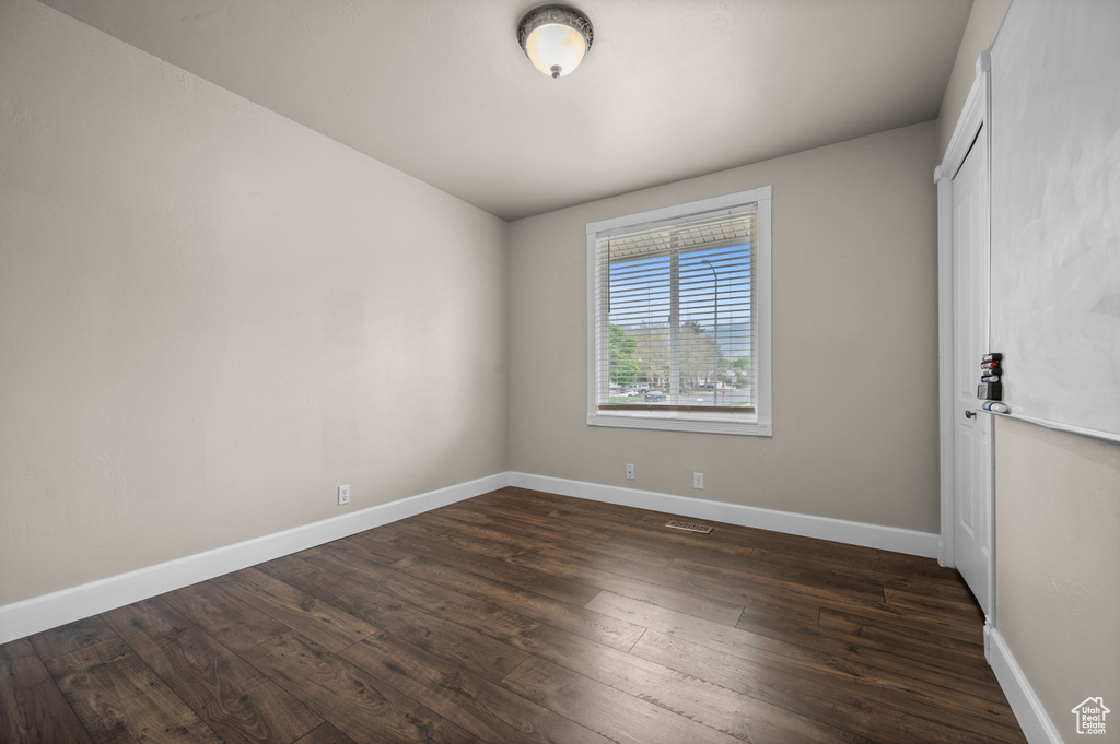 Empty room featuring dark wood-type flooring and baseboards