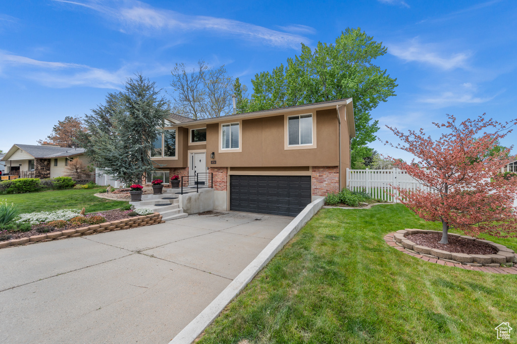 Split foyer home featuring an attached garage, stucco siding, and driveway