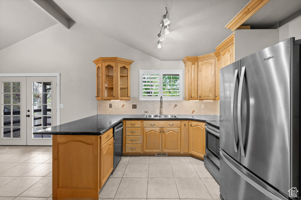 Kitchen featuring stainless steel appliances, a sink, a peninsula, light tile patterned floors, and tasteful backsplash
