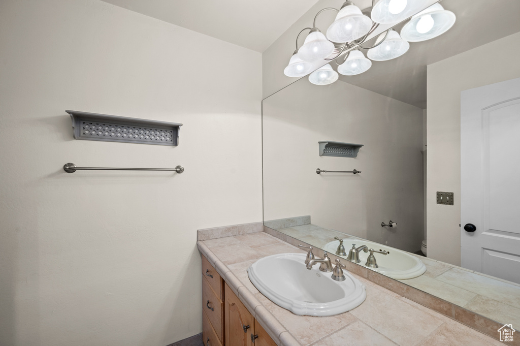 Bathroom featuring toilet, a chandelier, and vanity