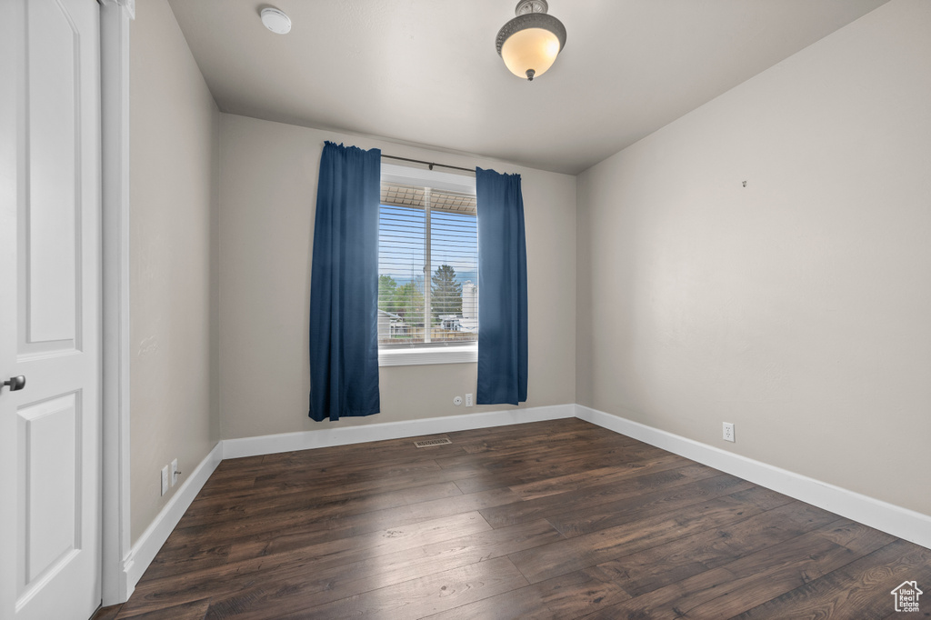 Empty room featuring dark wood-style floors and baseboards