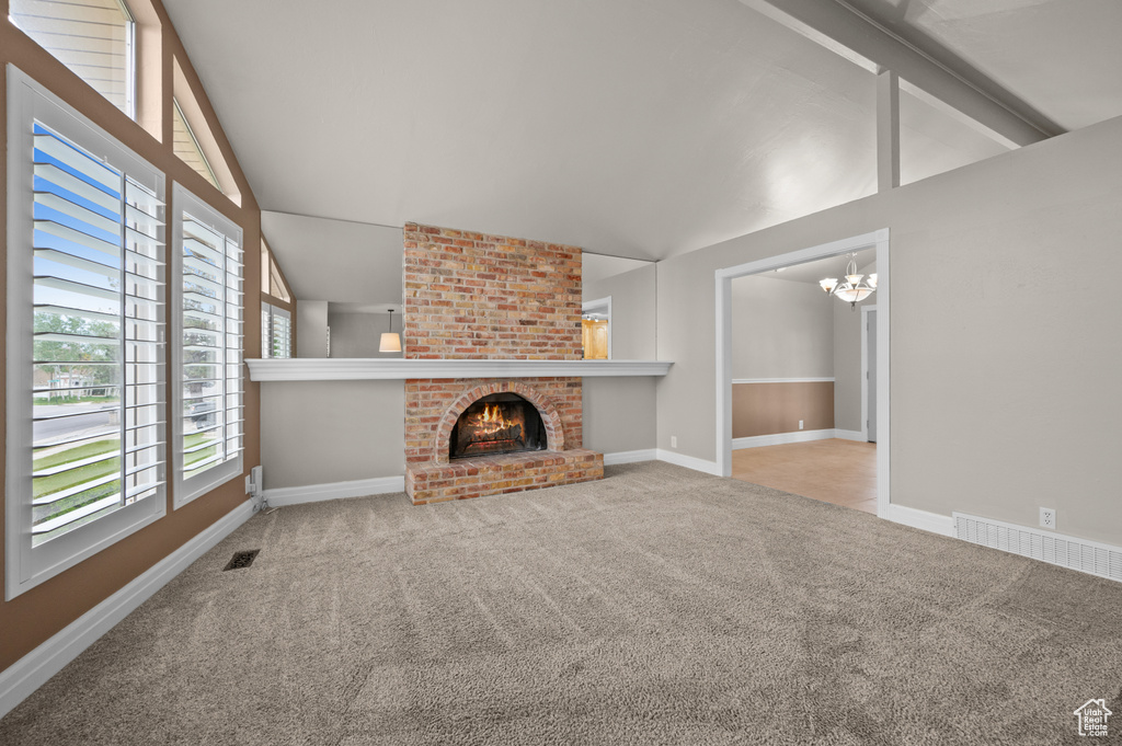 Unfurnished living room featuring a chandelier, carpet floors, baseboards, and a brick fireplace