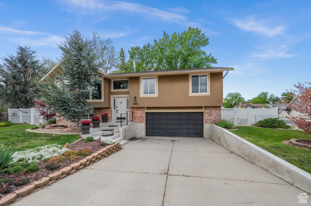 Bi-level home with an attached garage, driveway, stucco siding, and brick siding