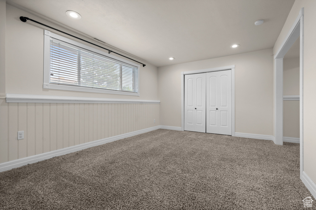 Unfurnished bedroom featuring carpet floors, a closet, a wainscoted wall, recessed lighting, and baseboards